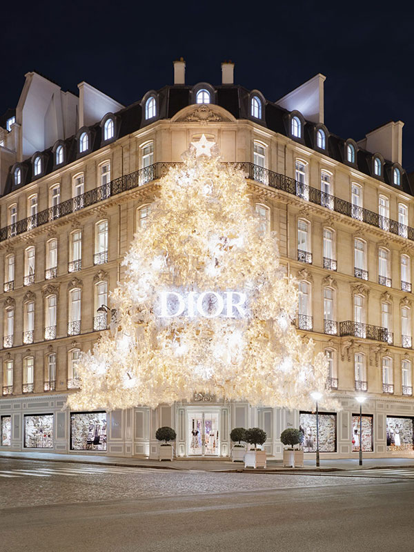 Two people walk past the holiday window display at the Dior store