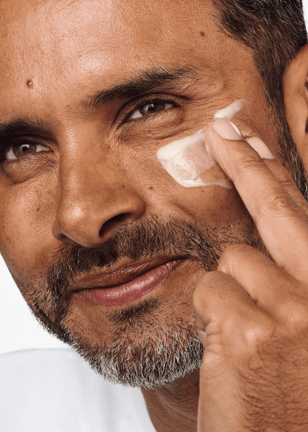 A man applying a lotion type moisturiser as part of a man's skincare routine.