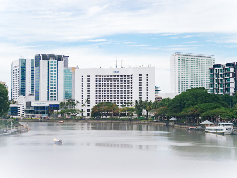 A riverside view of modern Kuching featuring the Hilton hotel.