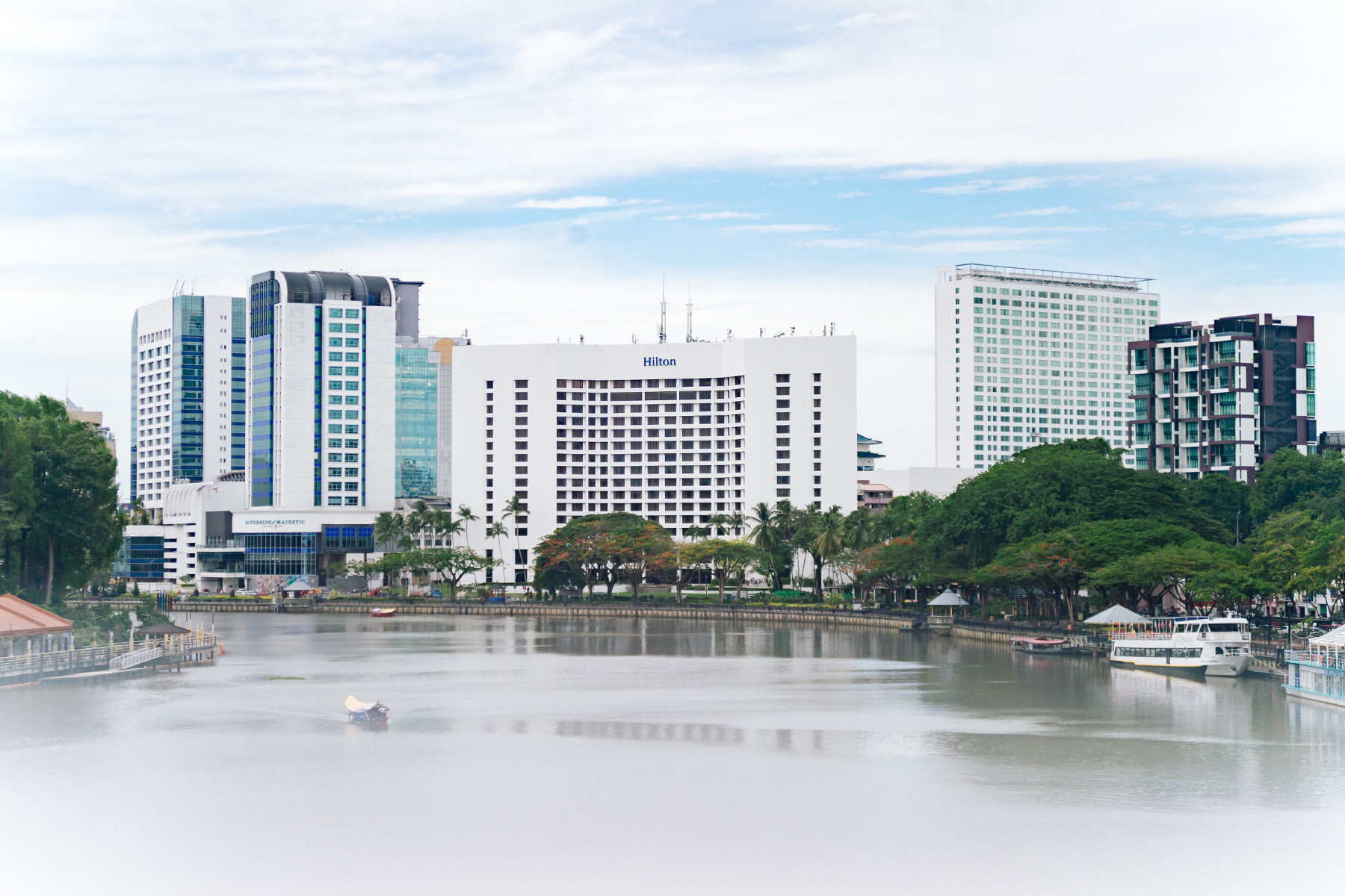 A riverside view of modern Kuching featuring the Hilton hotel.
