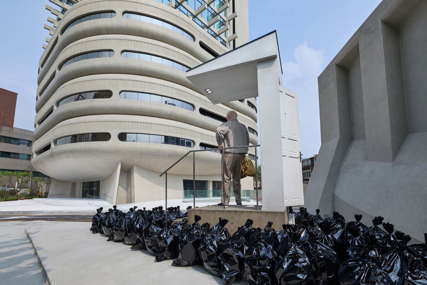 An installation titled More Is More transforms the room into a sea of black plastic bags.
