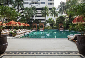 The 25-metre pool terrace at Anantara Siam Bangkok, with teak cabanas, palms and the city beyond.