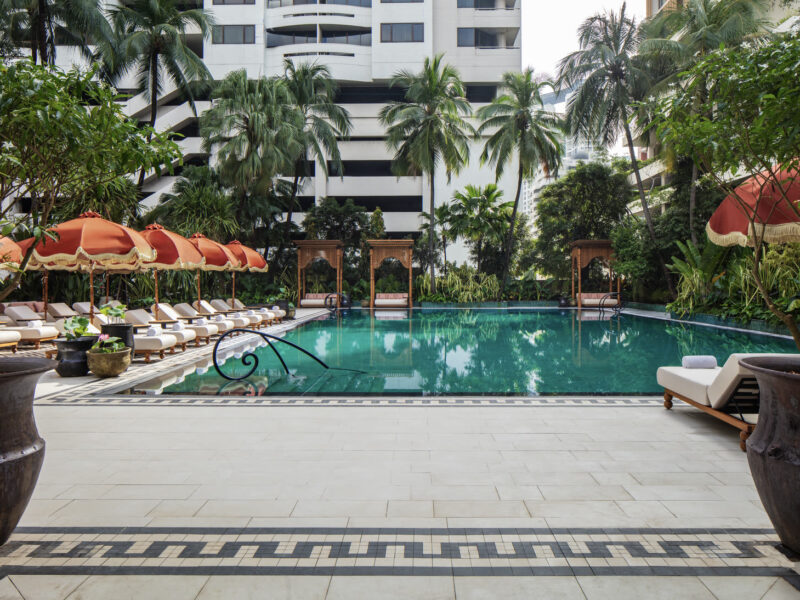 The 25-metre pool terrace at Anantara Siam Bangkok, with teak cabanas, palms and the city beyond.