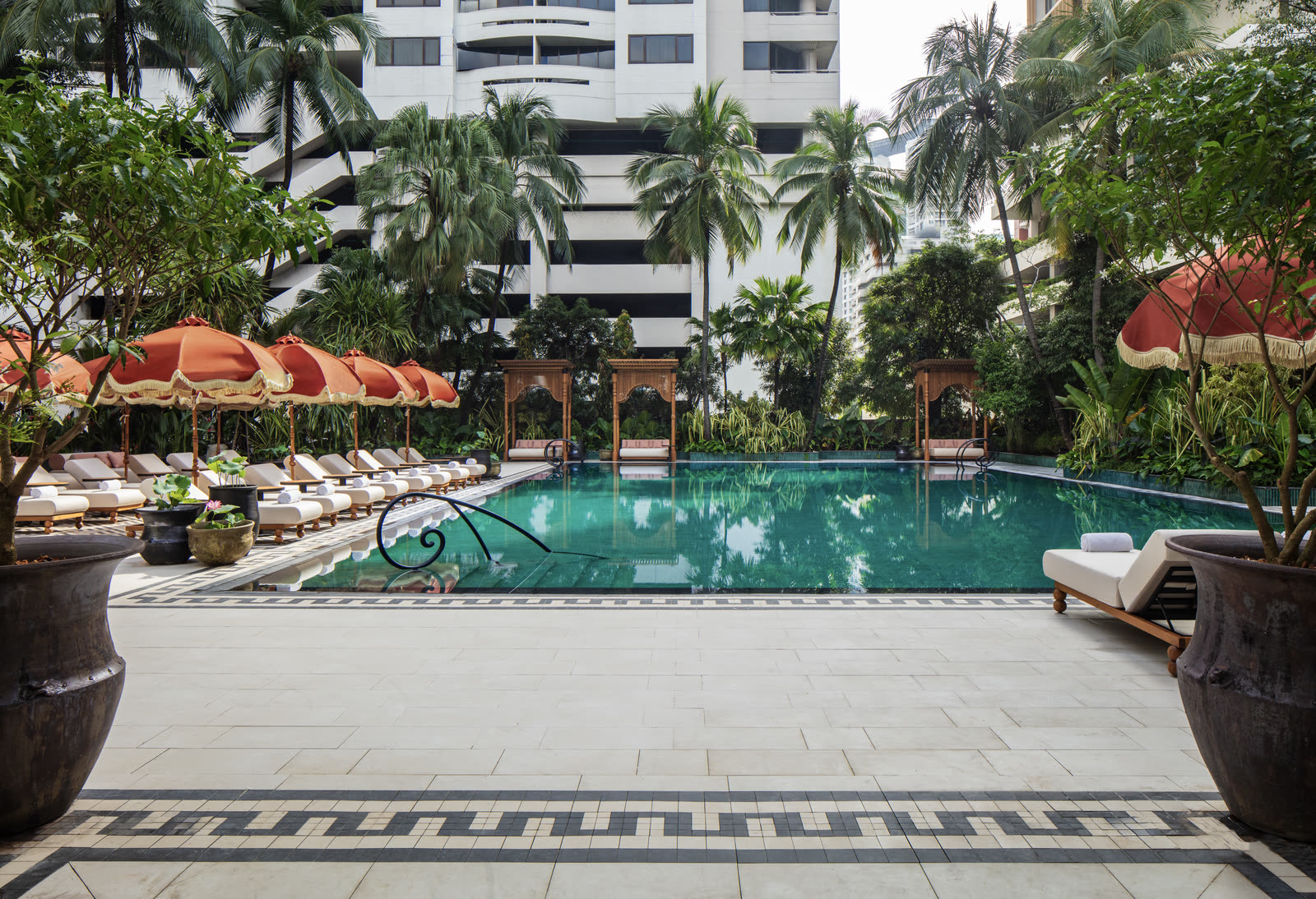 The 25-metre pool terrace at Anantara Siam Bangkok, with teak cabanas, palms and the city beyond.