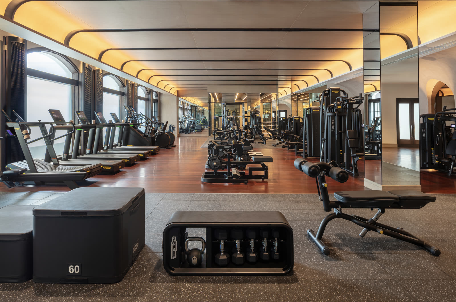 The health club at Anantara Siam Bangkok, with Technogym equipment under tall arched windows.